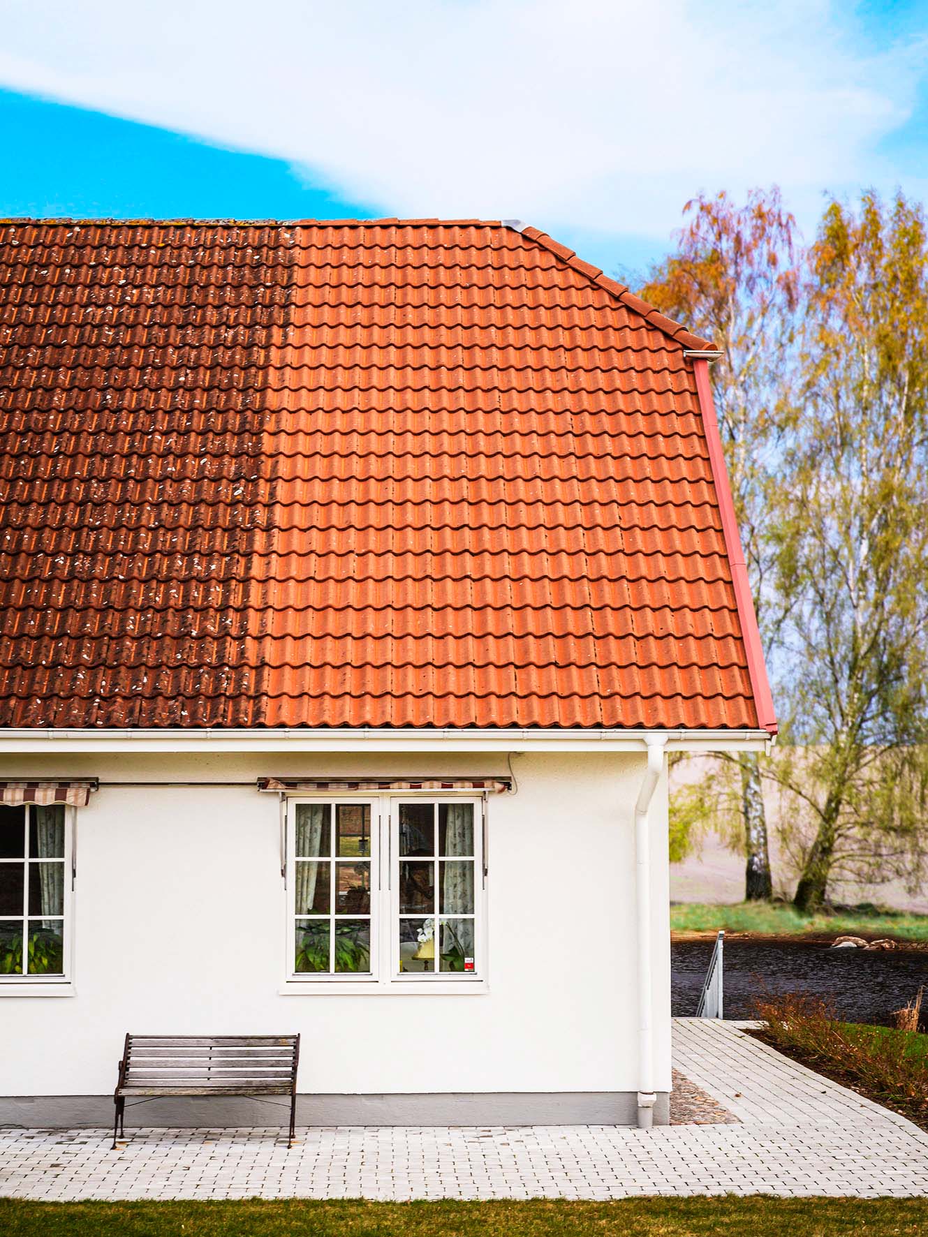 Ett hus där halva tegeltaket har genomgått en taktvätt av Ultraputs och är rent från mossa, medan den andra halvan fortfarande är smutsig, vilket visar ett tydligt före- och efterresultat.